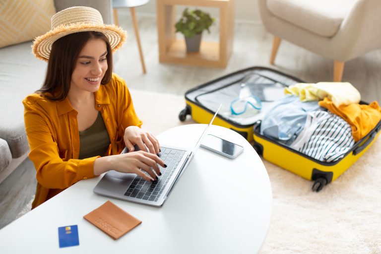Cool young woman planning vacation travel with laptop, reading tourist blog online, booking tickets or hotel room on web